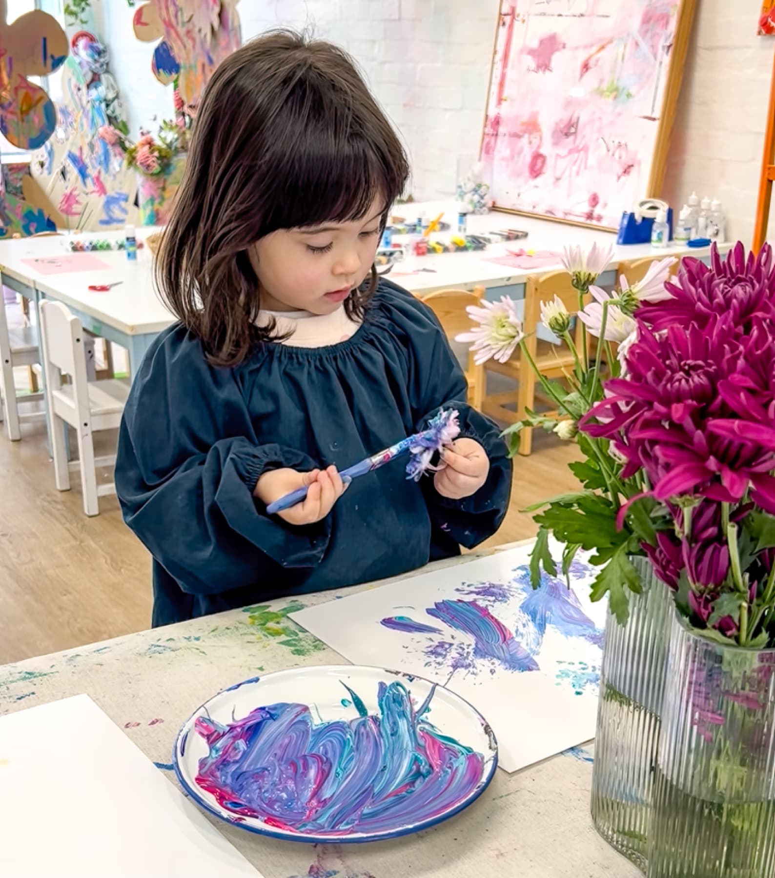 Child painting with flowers in studio