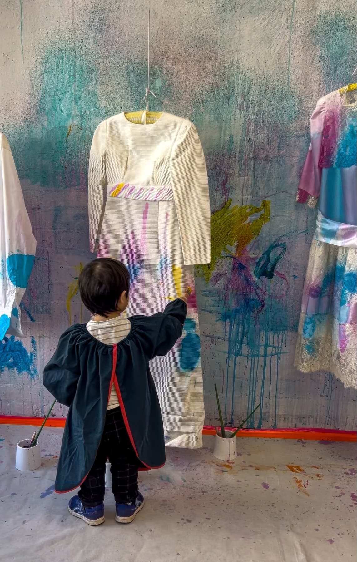 Child painting hanging dresses