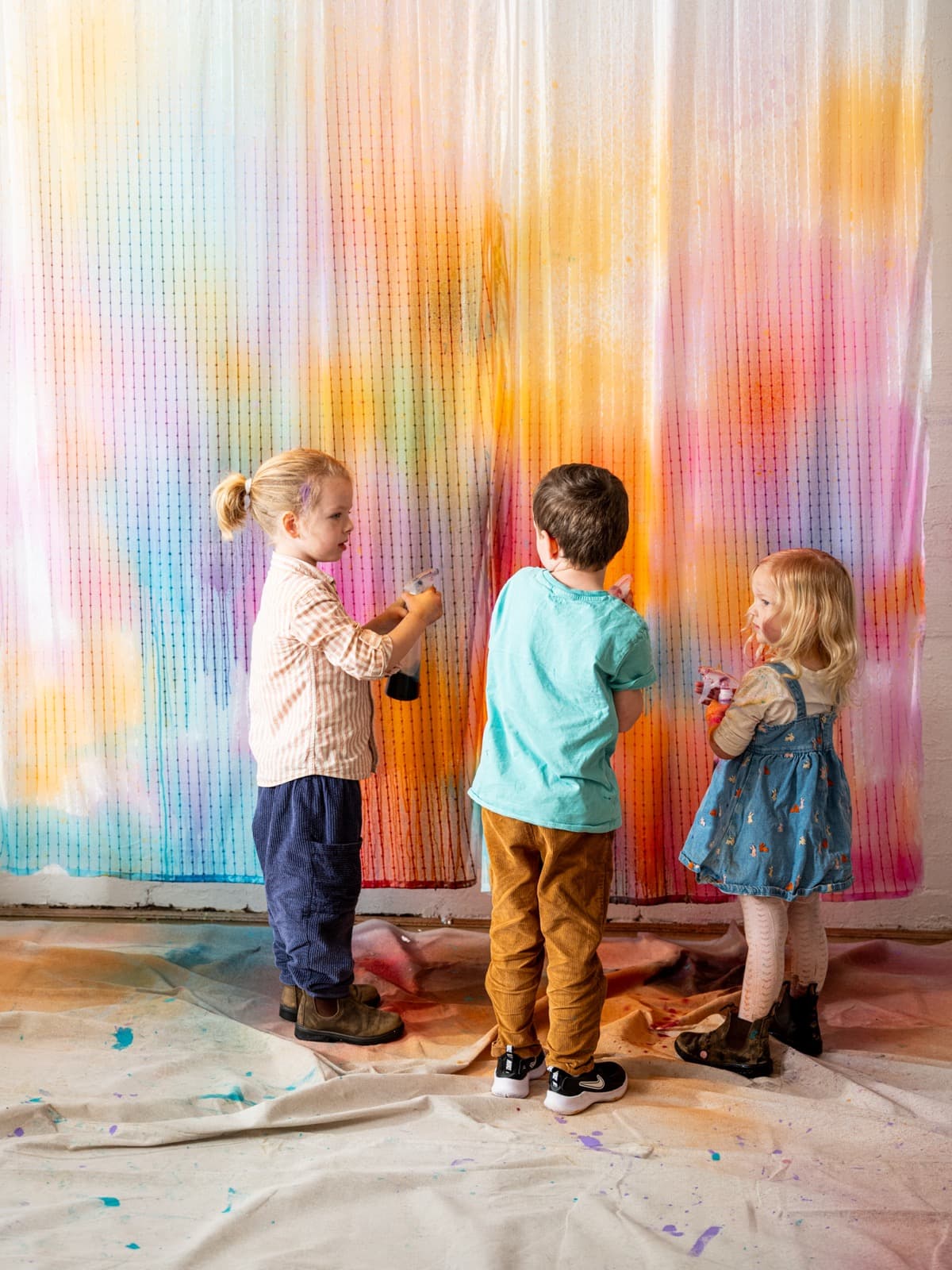 Kids painting on a large wall canvas