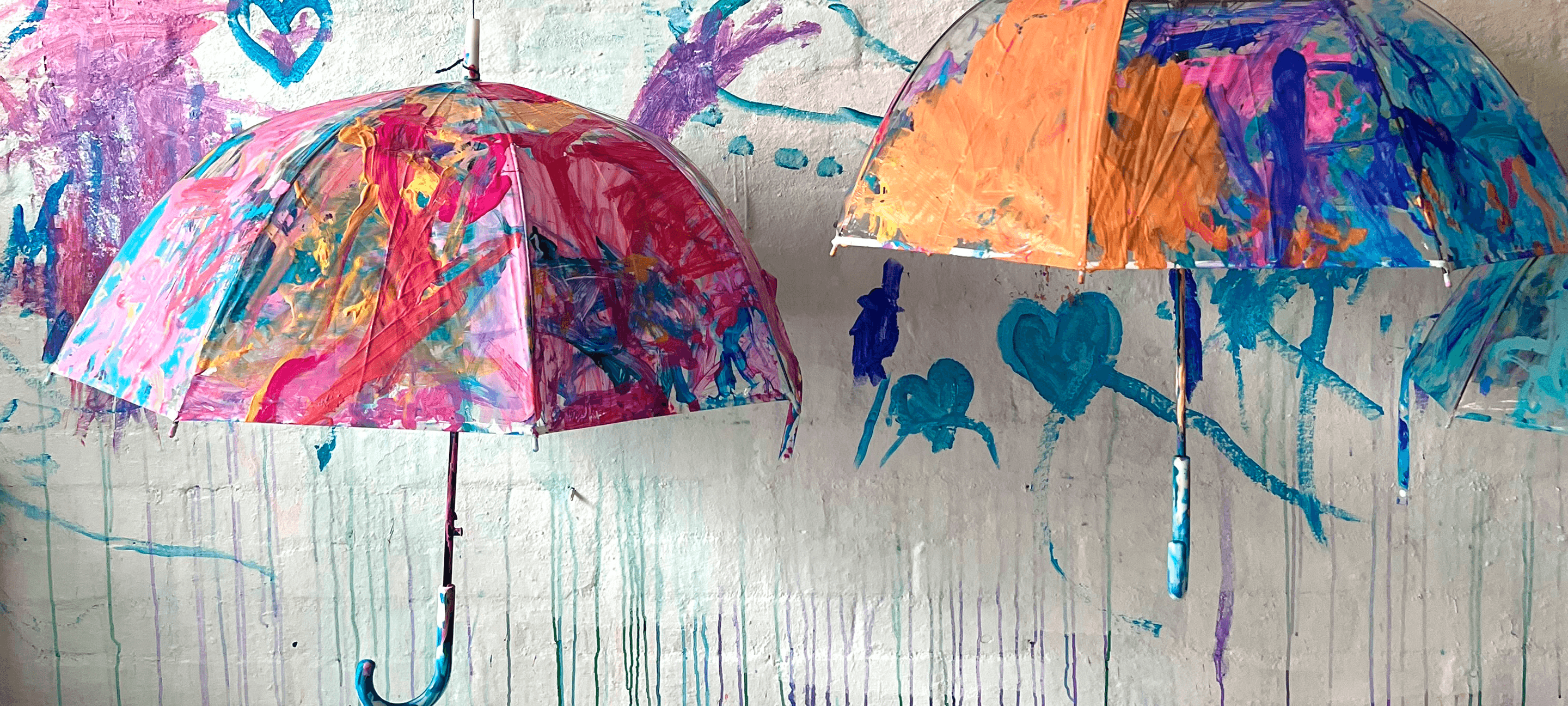 Two umbrellas painted at Smudge, dripping pink, orange and blue.